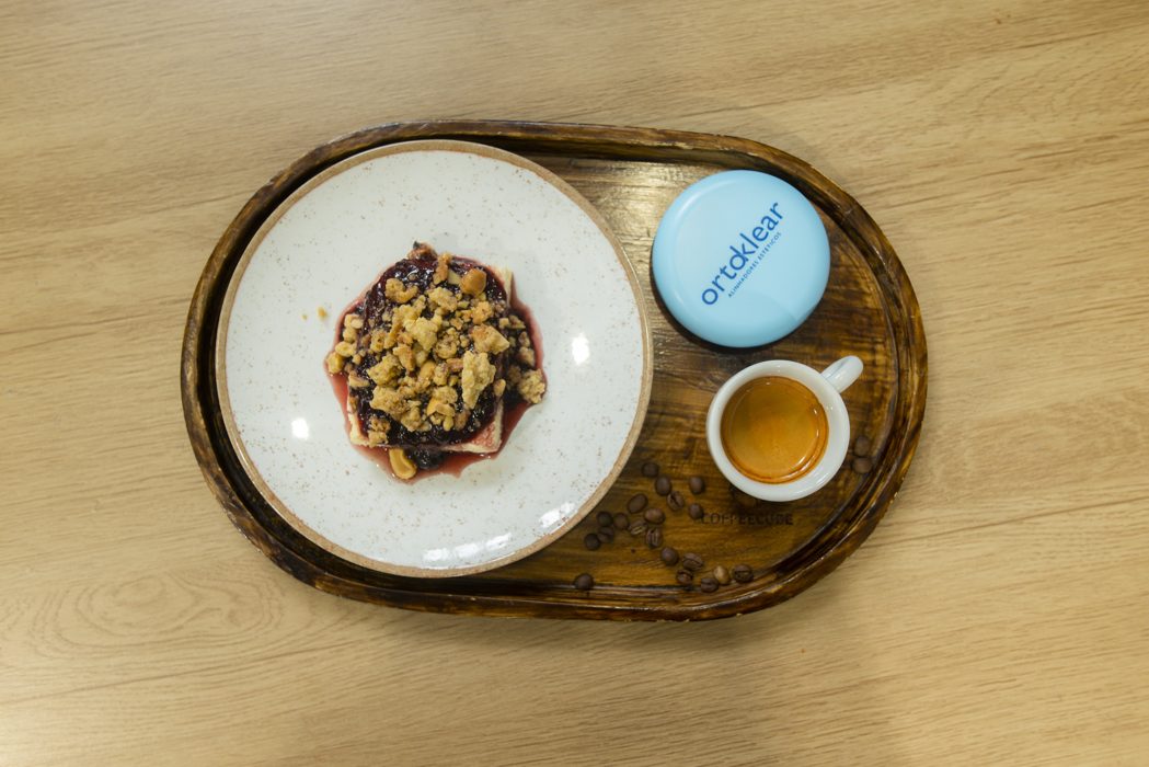 Estojo Ortoklear ao lado de café e sobremesa em uma cafeteria